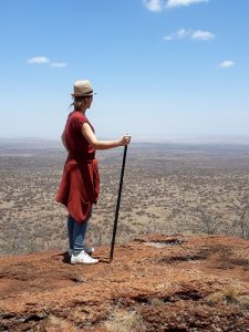 Eine Frau steht auf einer Anhöhe in der Amboseli-Region und blickt in die Ferne.